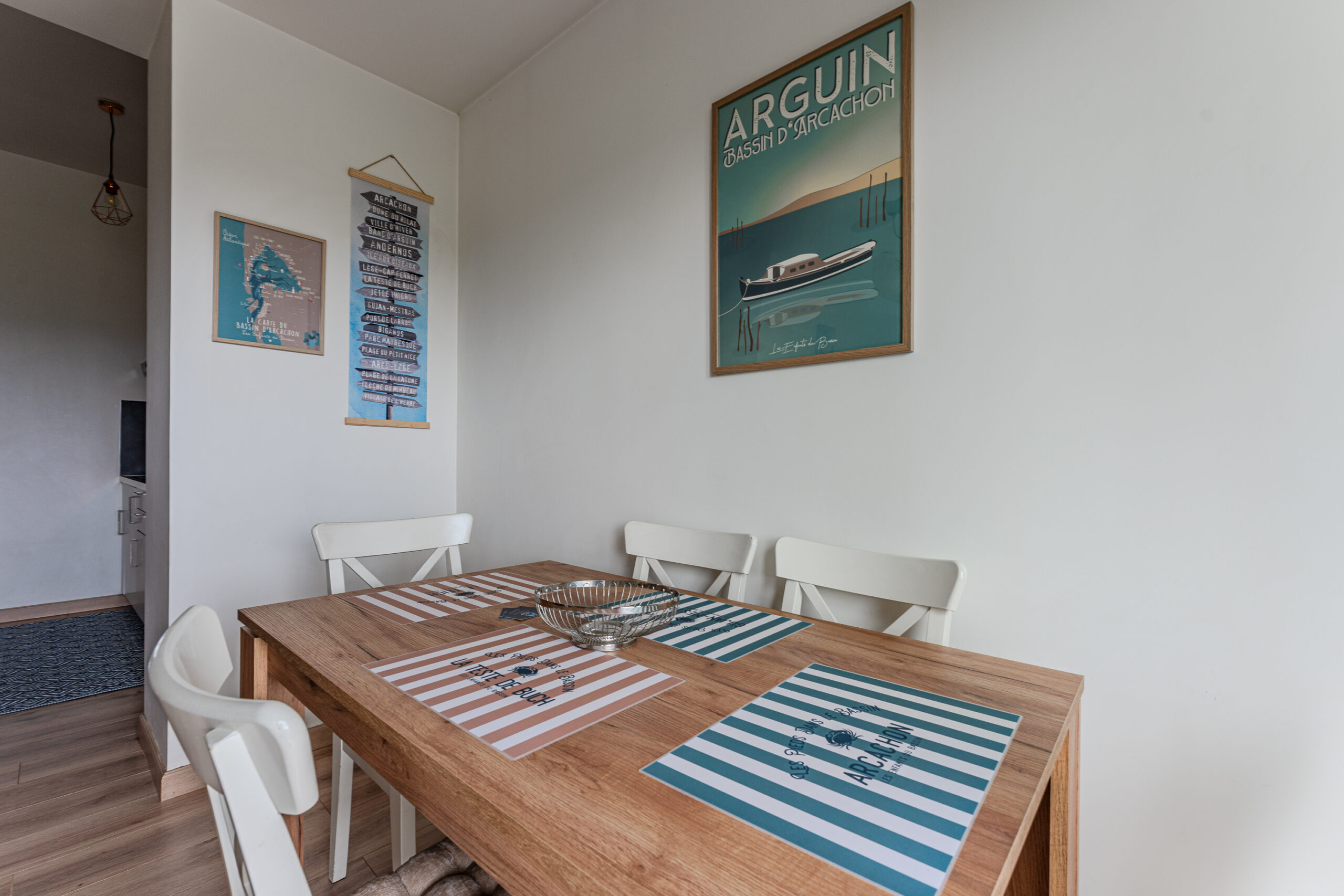 Image de la salle à manger dans notre appartement, montrant une table en bois clair entourée de chaises confortables sous un éclairage chaleureux, idéale pour des repas conviviaux. La pièce est décorée avec goût dans un esprit Bassin, combinant des éléments contemporains et traditionnels, créant une ambiance accueillante pour des vacances en couple ou en famille.